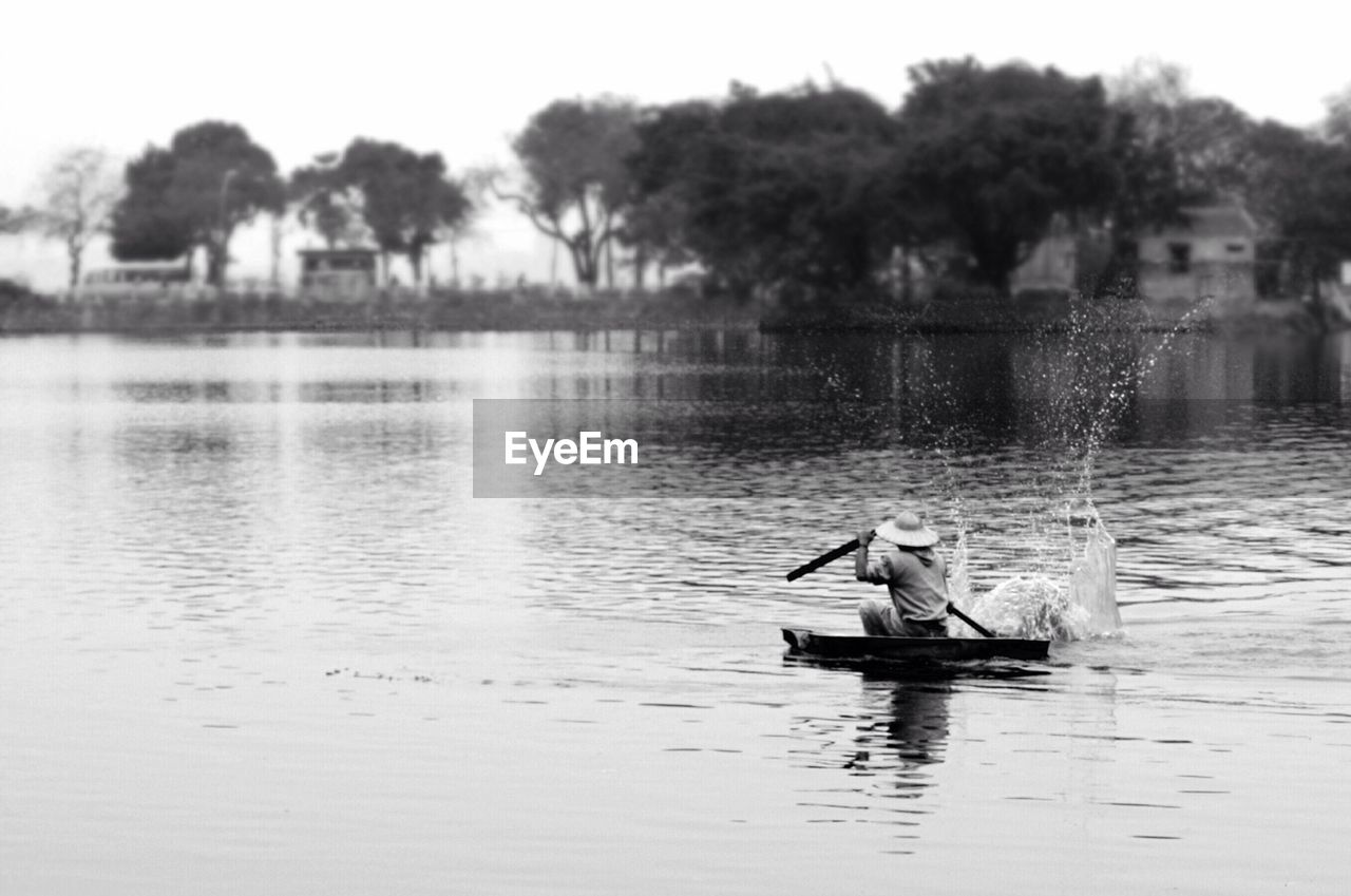 Rear view of man sailing boat in lake