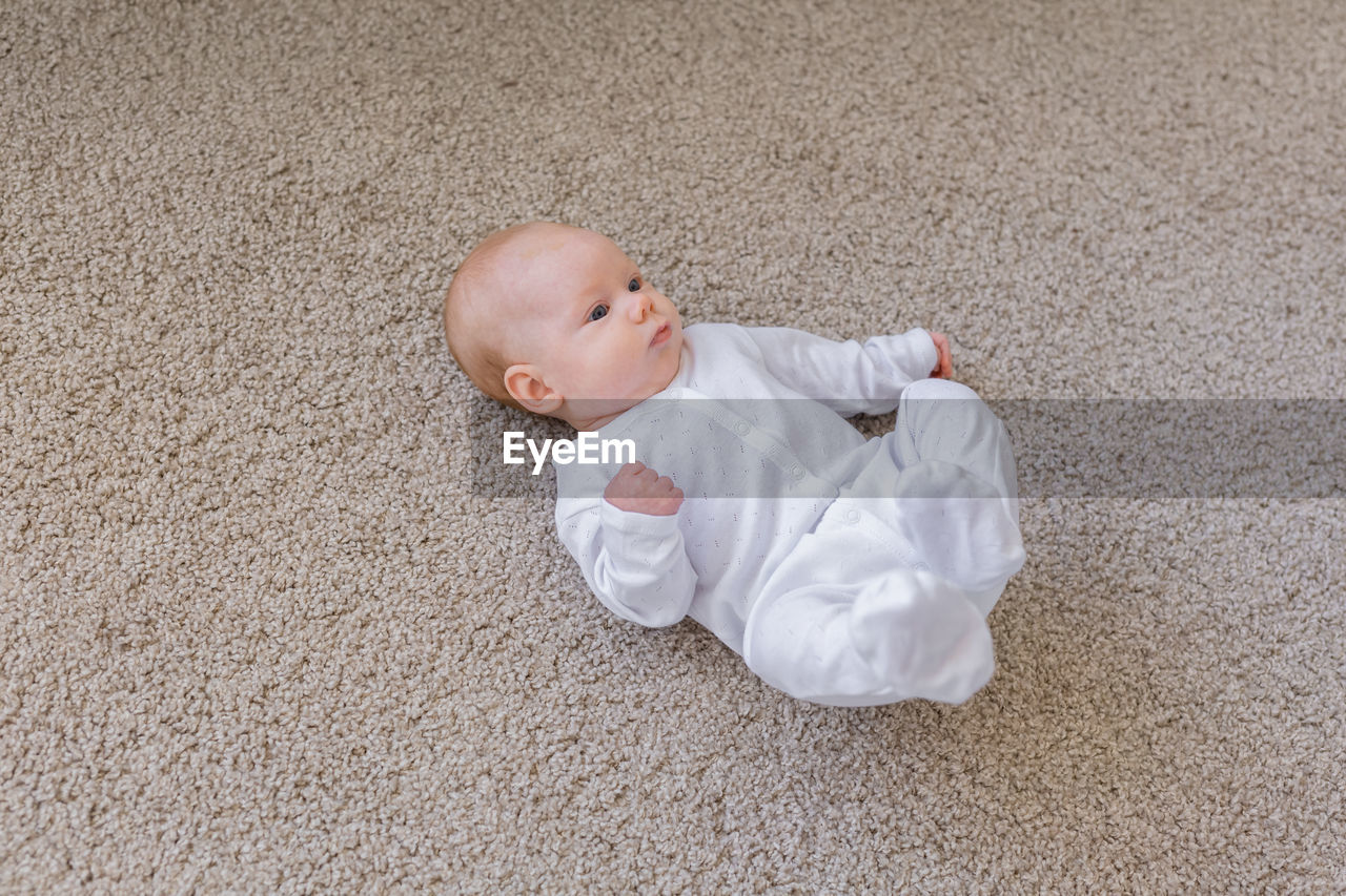 HIGH ANGLE VIEW OF CUTE BABY LYING DOWN ON FLOOR