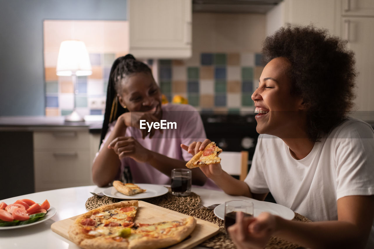 Mixed race woman laughing at joke near friend