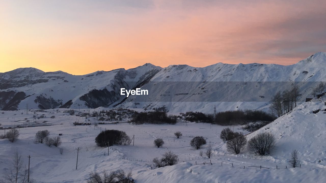 Scenic view of snow covered mountains against sky during sunset