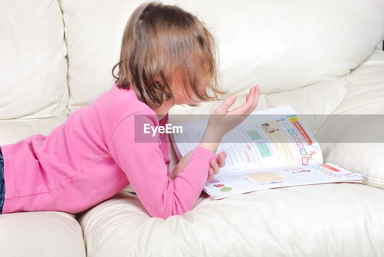 REAR VIEW OF GIRL SITTING ON BED