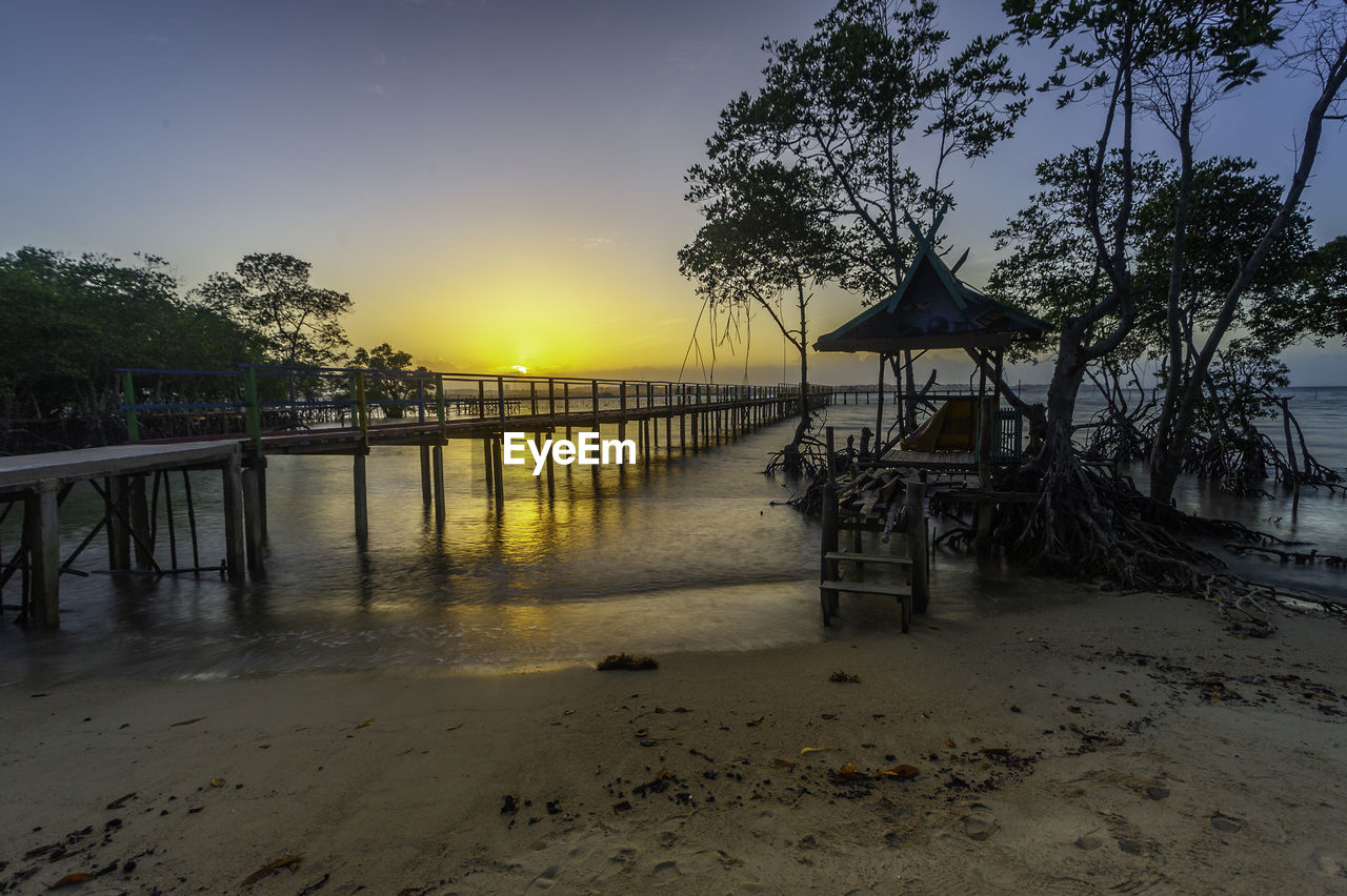 PIER ON BEACH AGAINST SKY DURING SUNSET