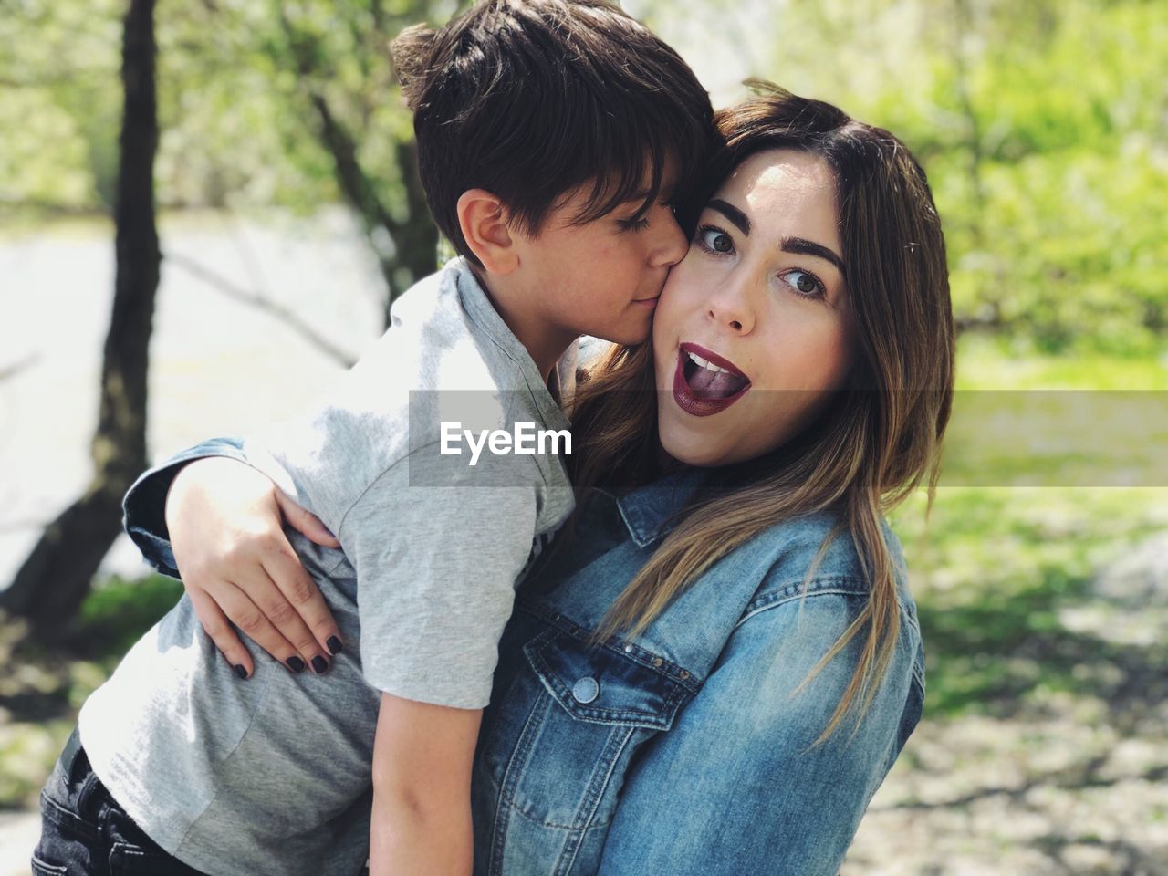 Portrait of boy kissing mother while standing outdoors