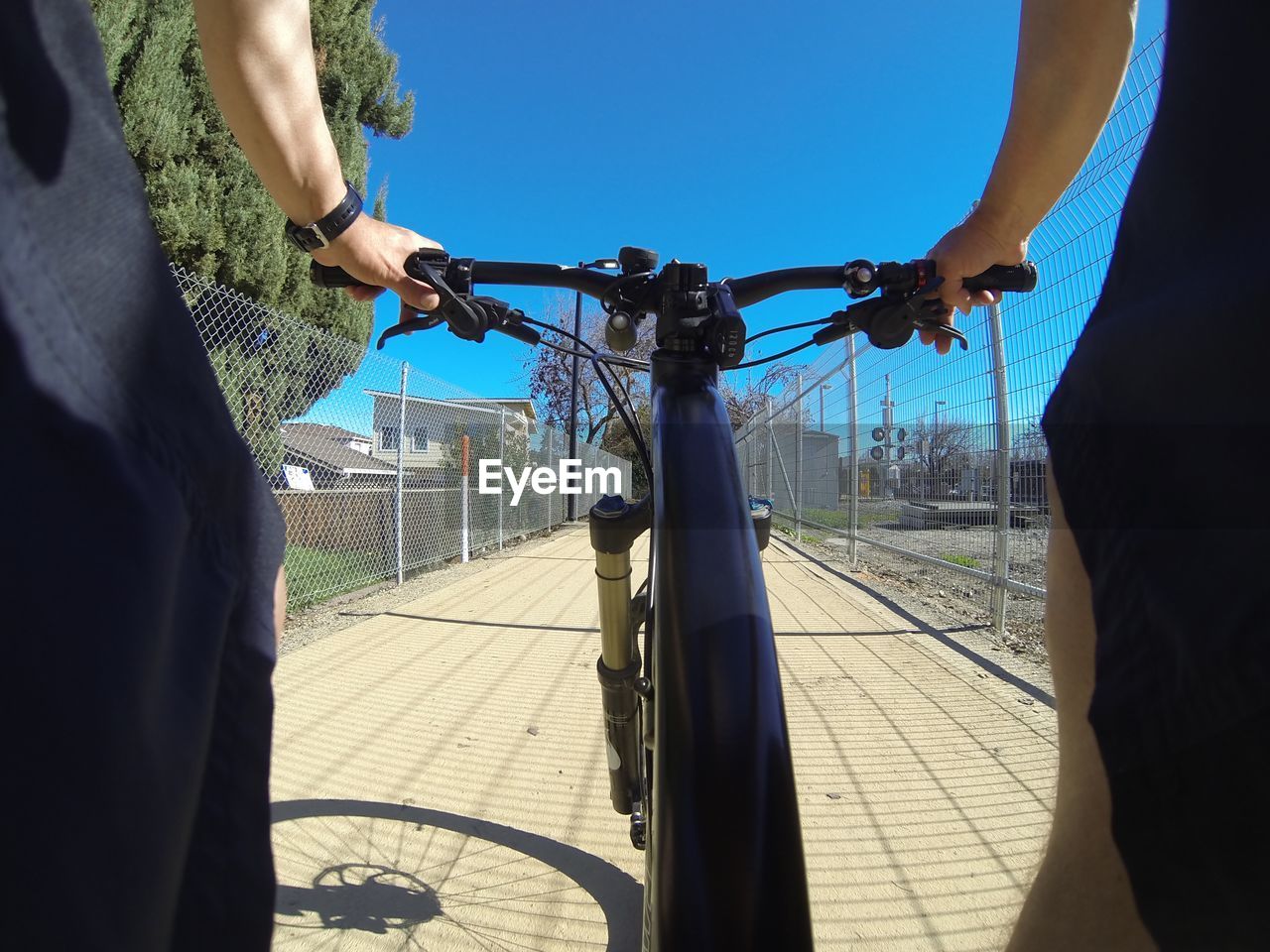 Man riding bicycle on footpath against clear blue sky