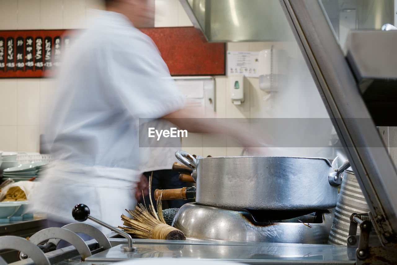 MIDSECTION OF MAN WORKING IN KITCHEN