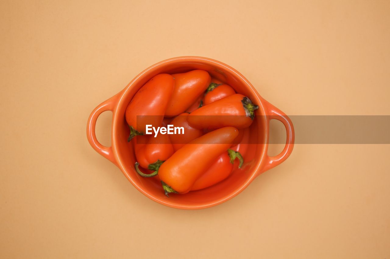 Close-up of red peppers in bowl over beige background