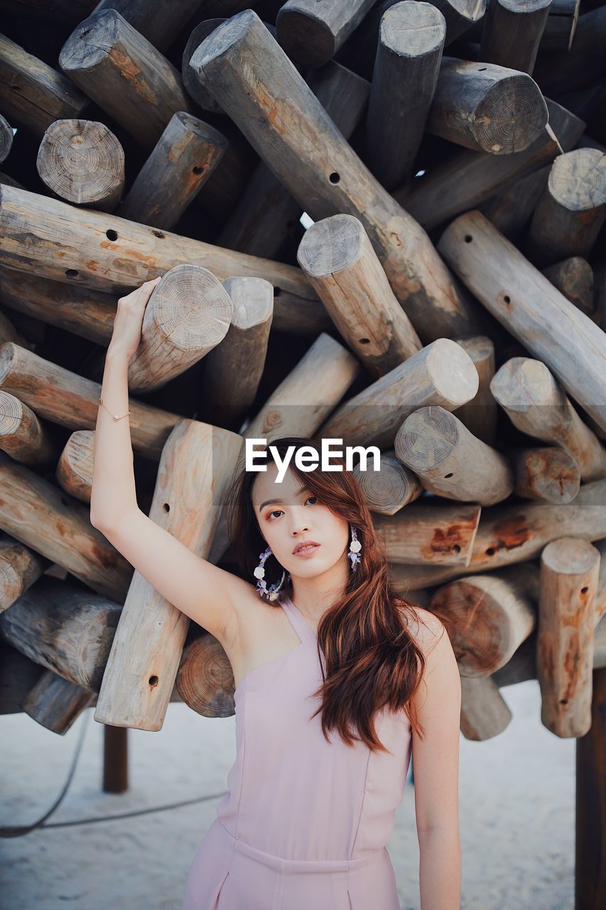 Portrait of woman standing against wooden logs