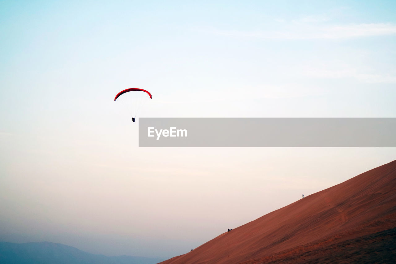 Low angle view of person paragliding against clear sky