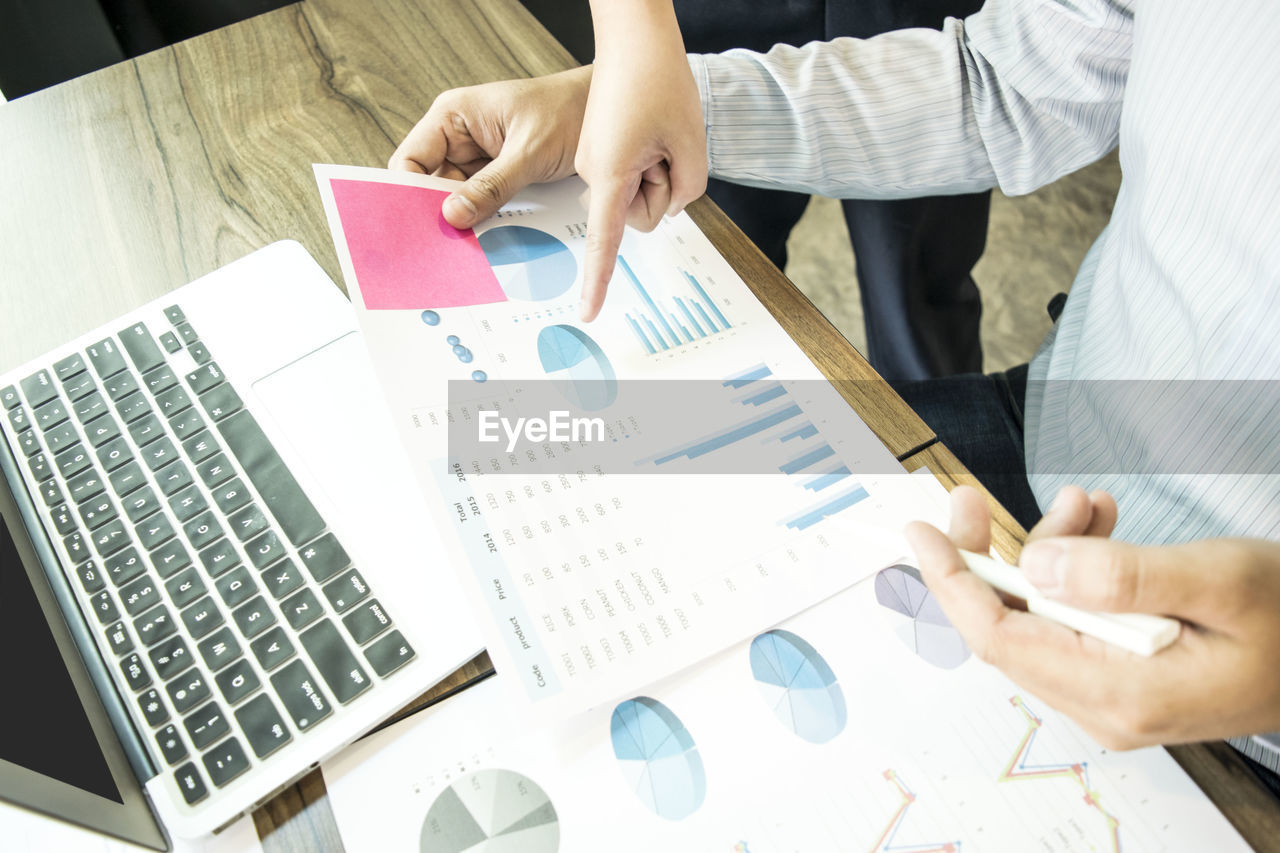 High angle view of business people working over graphs and charts at desk in office