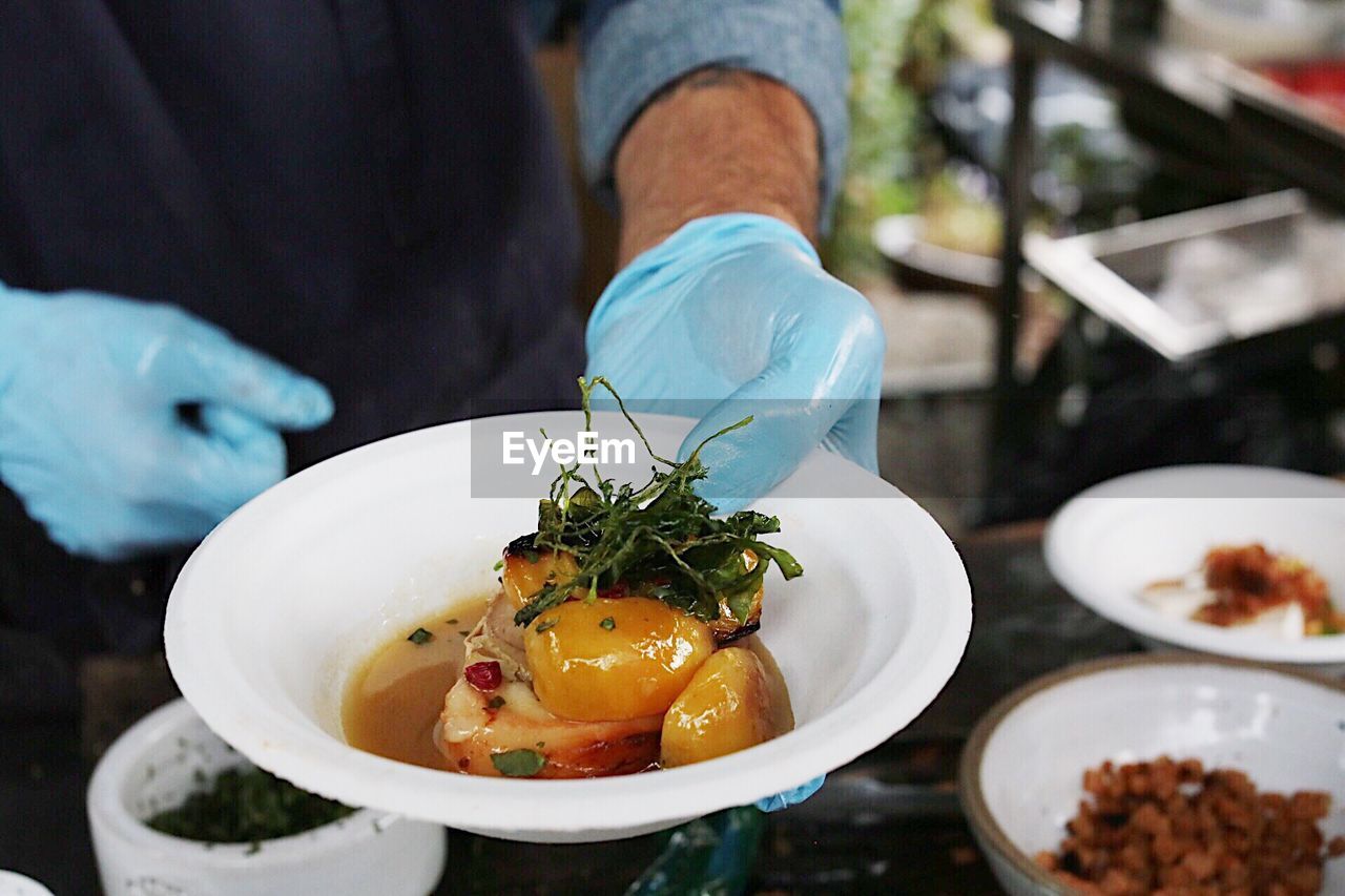 Midsection of man holding meat in bowl at table