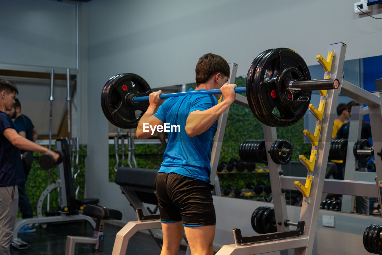 Young man preparing for squat at gym