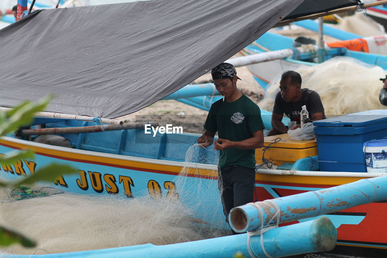 People and boat, fixing net