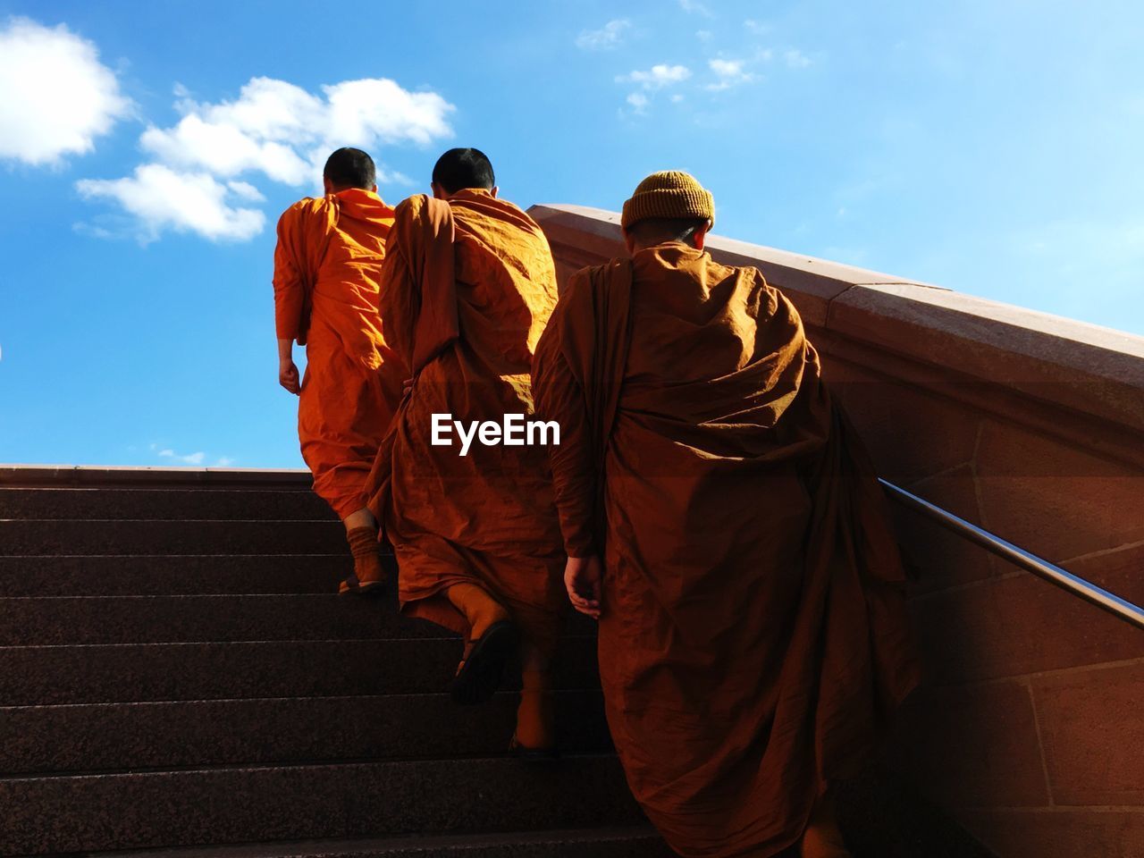 Rear view of monks walking on steps against sky