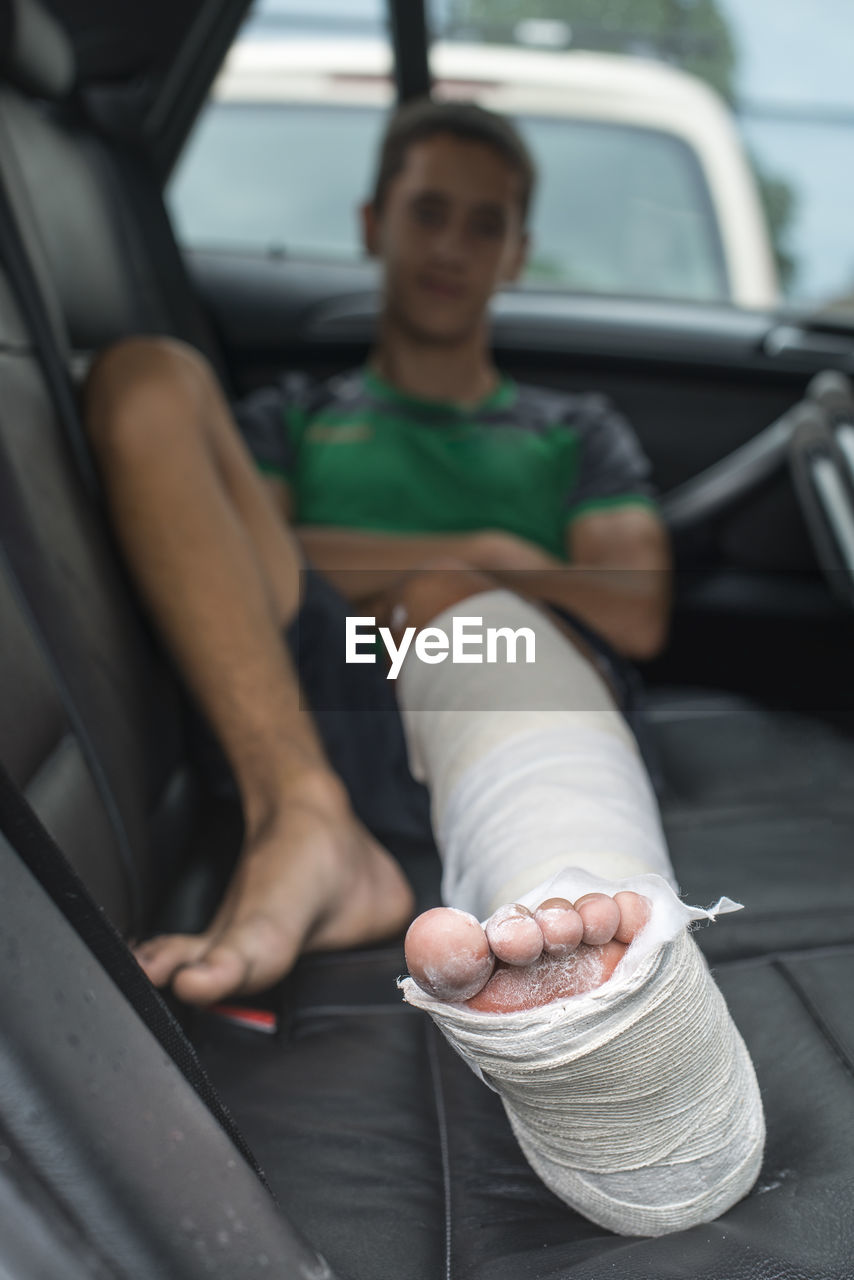 Boy with broken leg sitting in car