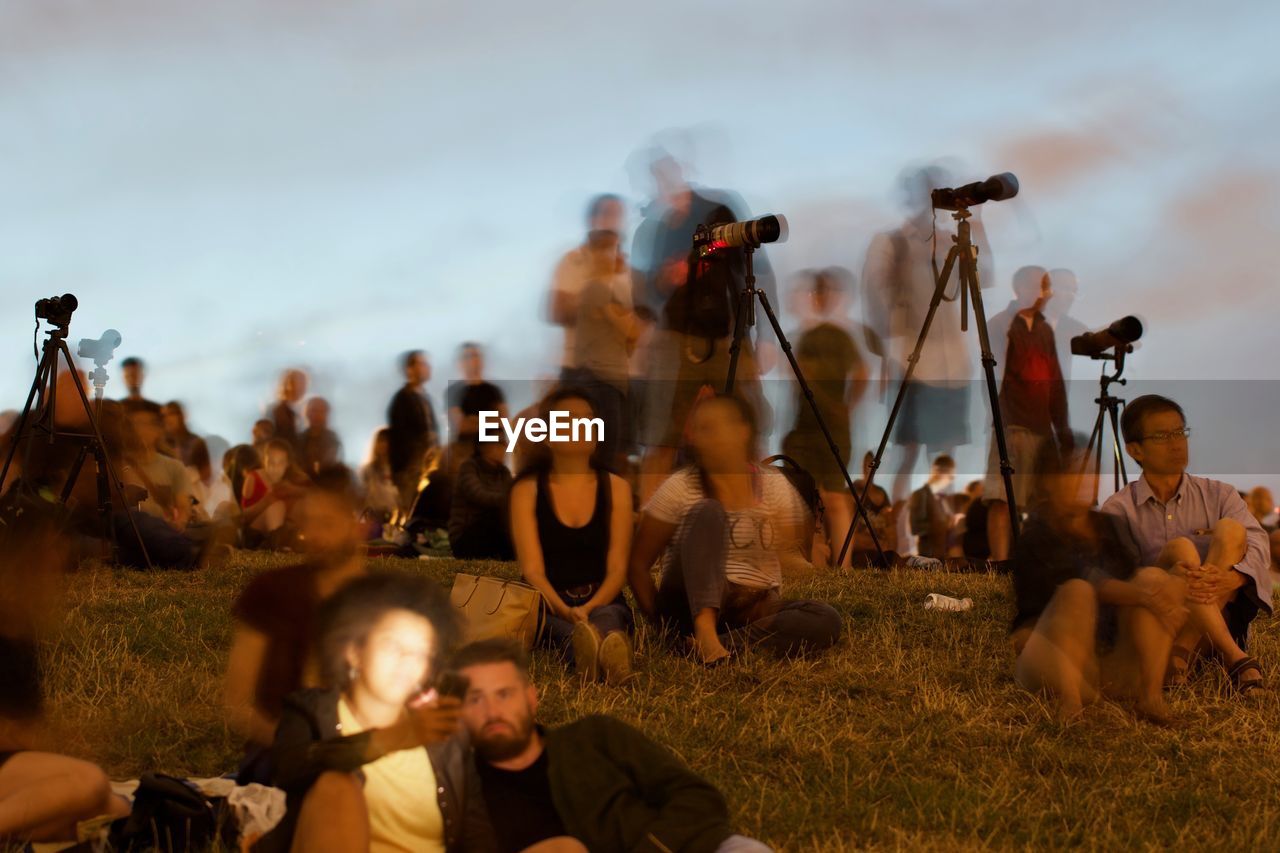 GROUP OF PEOPLE SITTING ON FIELD