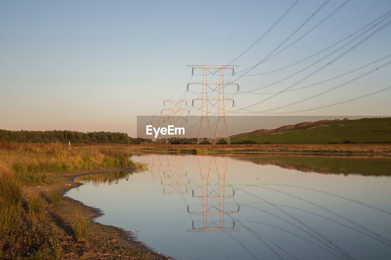 Reflection of electricity pylons on water during sunset