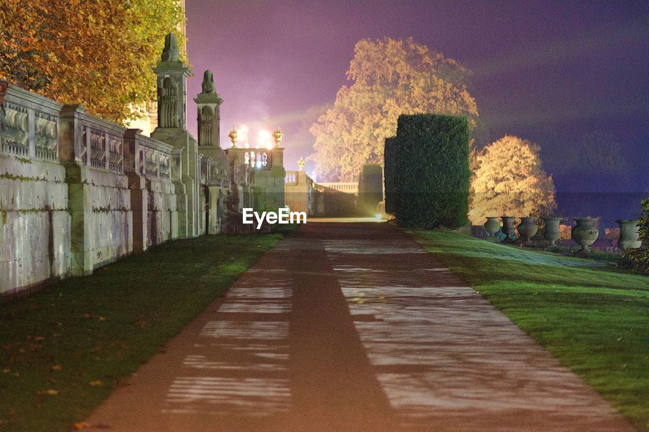 Empty footpath against sky at night