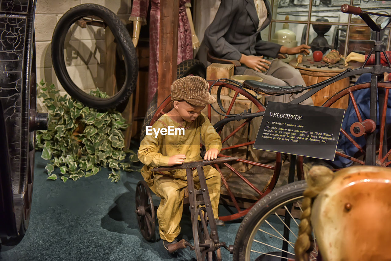 REAR VIEW OF MAN WITH BICYCLE SITTING ON STORE