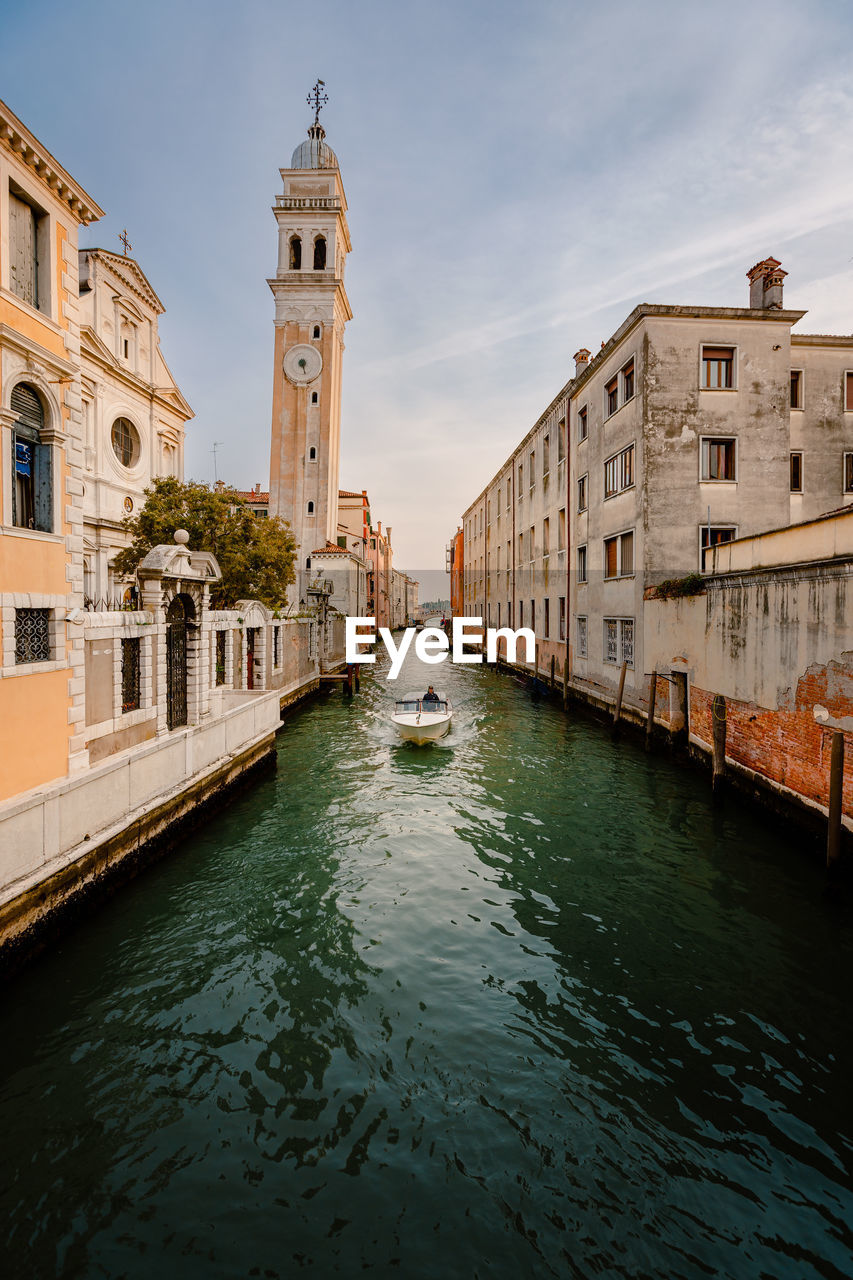 Motor boat sailing past the church of san giorgio dei greci with its typical leaning bell tower