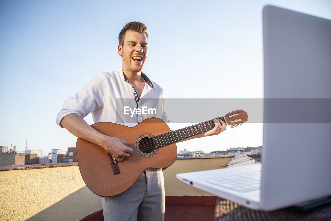 Handsome young singer performing for his fans on social media from the roof of his house during quarantine