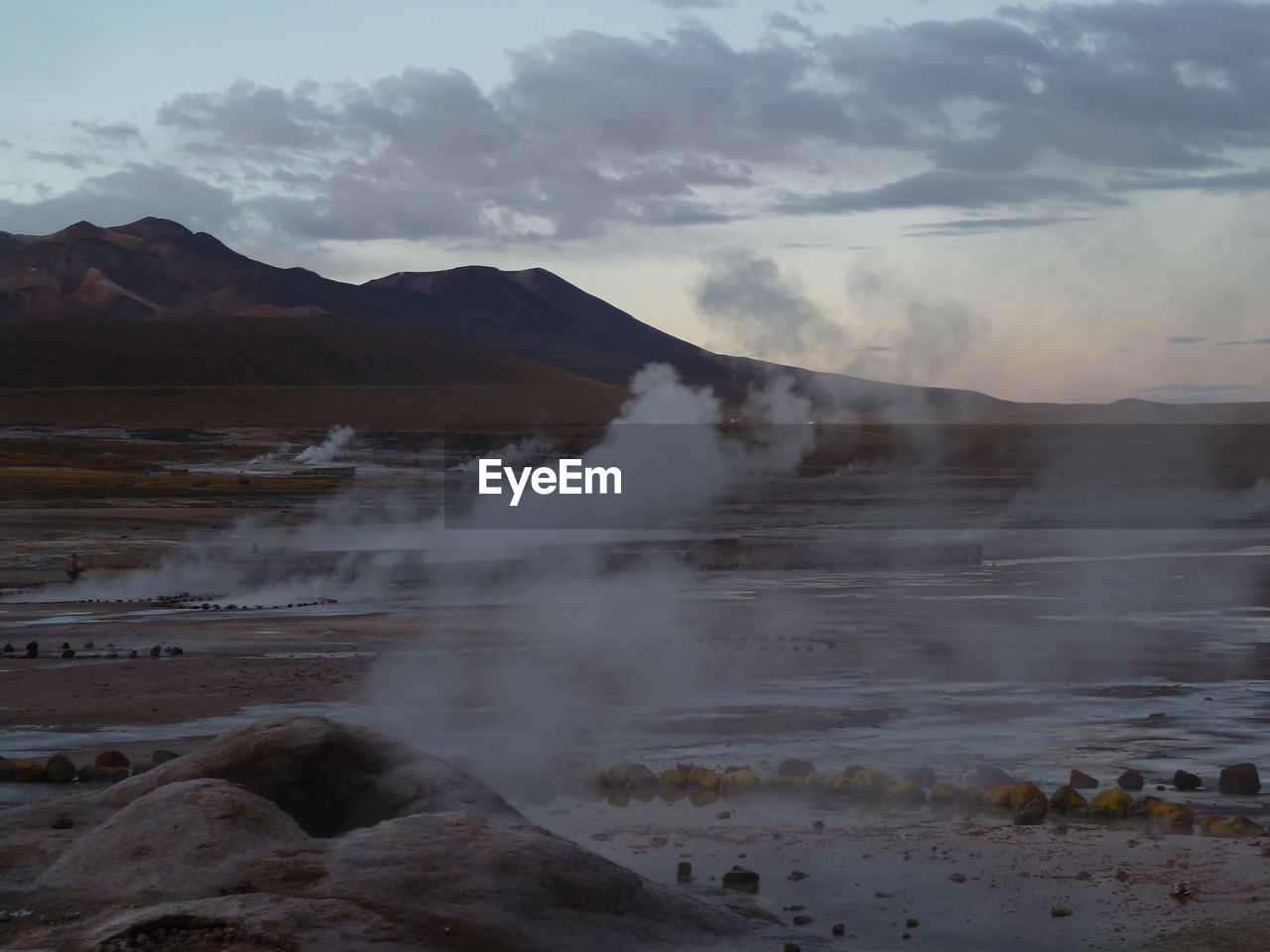 Geyser emitting from volcanic mountain against sky