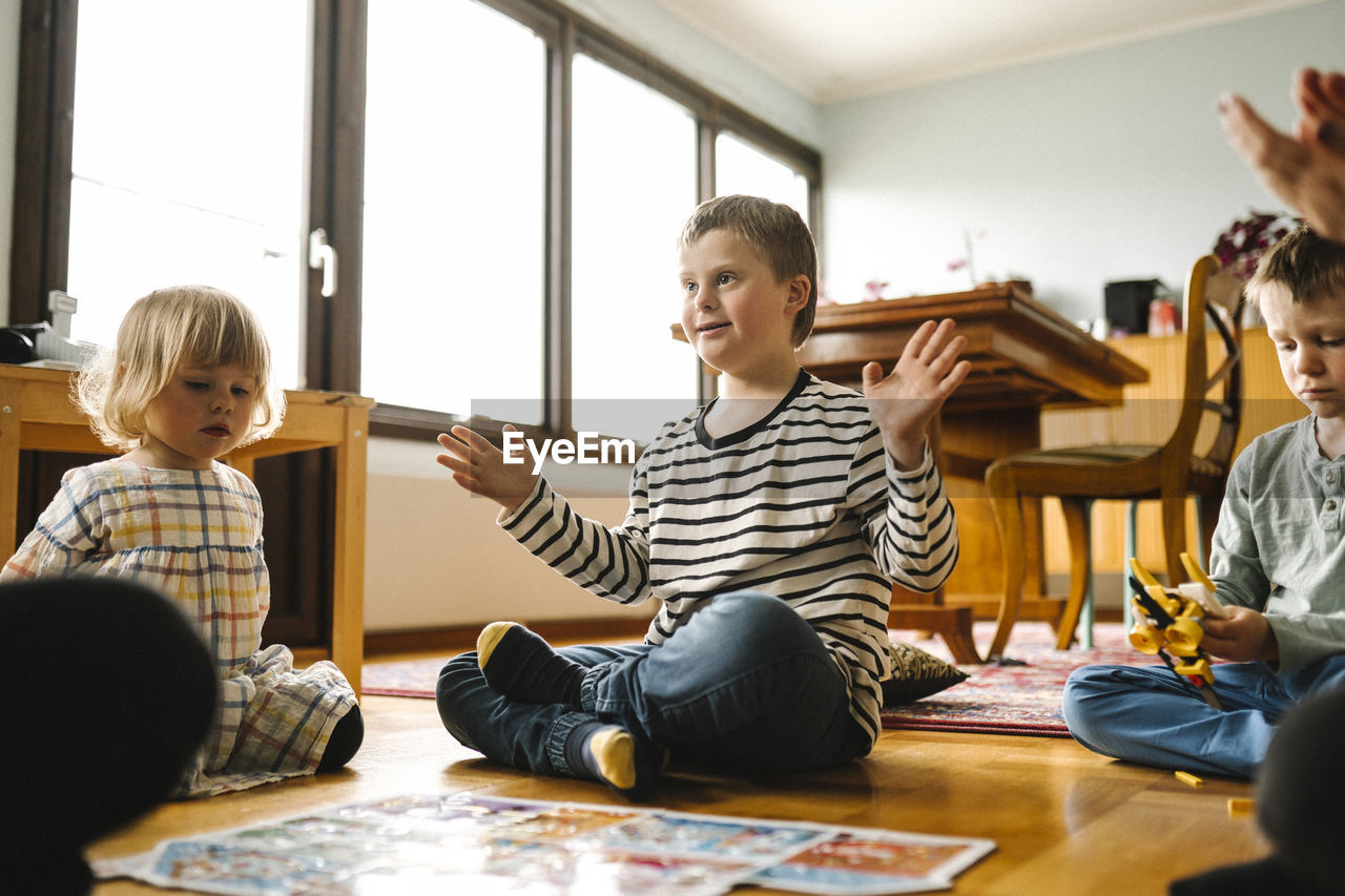 Boy having down syndrome completes jigsaw puzzle sitting with family in living room