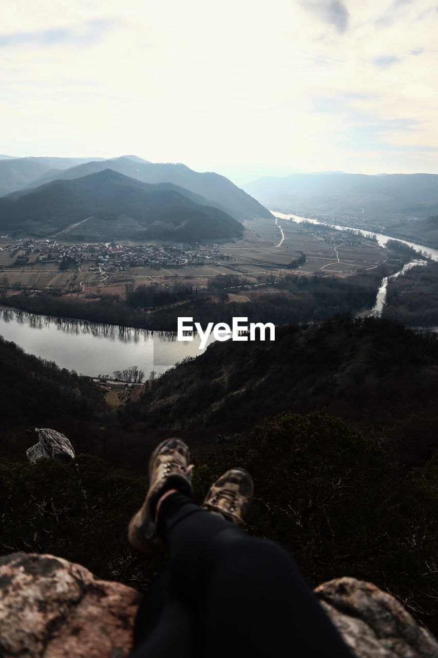 Low section of man on mountains against sky