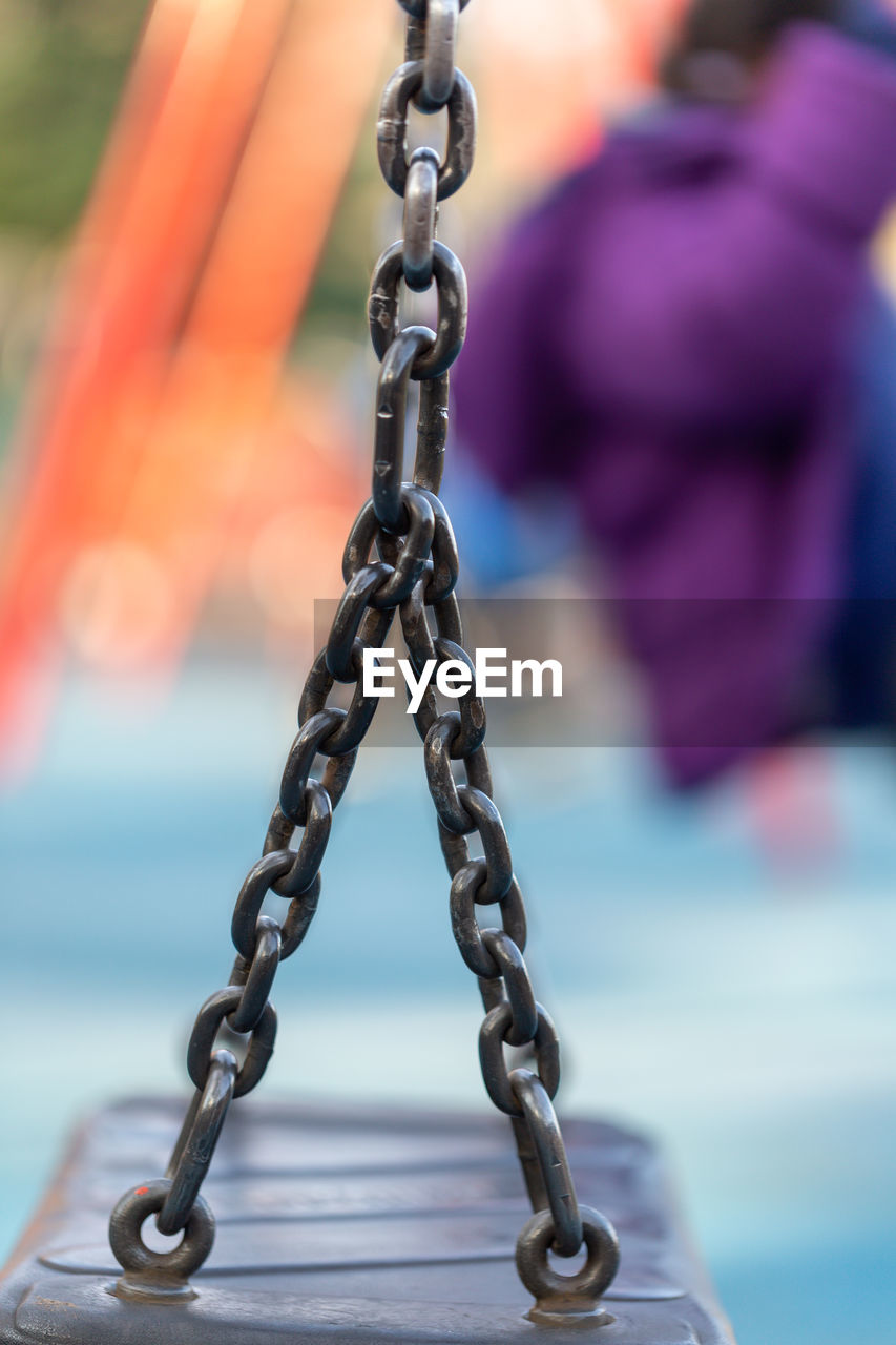 CLOSE-UP OF CHAIN SWING AGAINST SKY DURING SUNSET