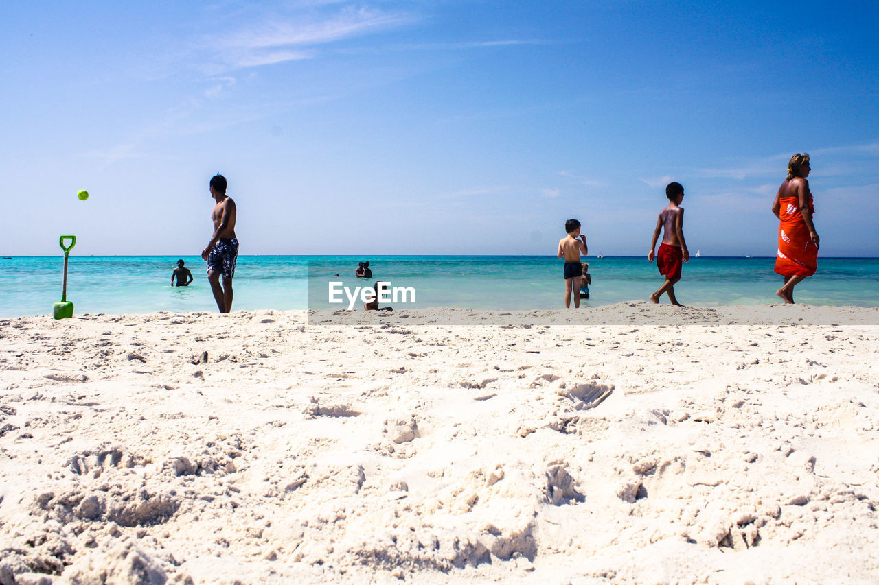 People enjoying at beach against sky