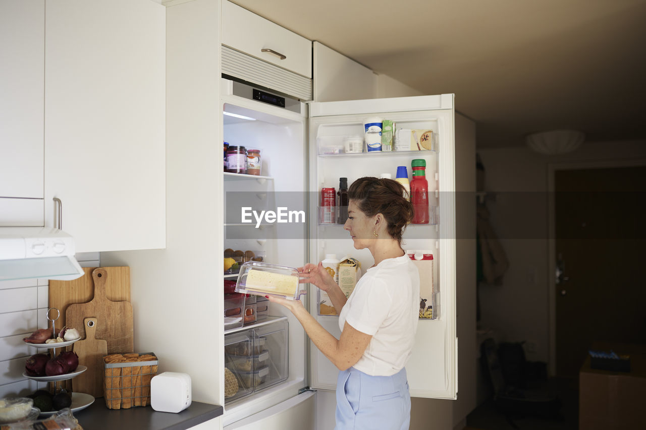 Woman standing in front of open fridge