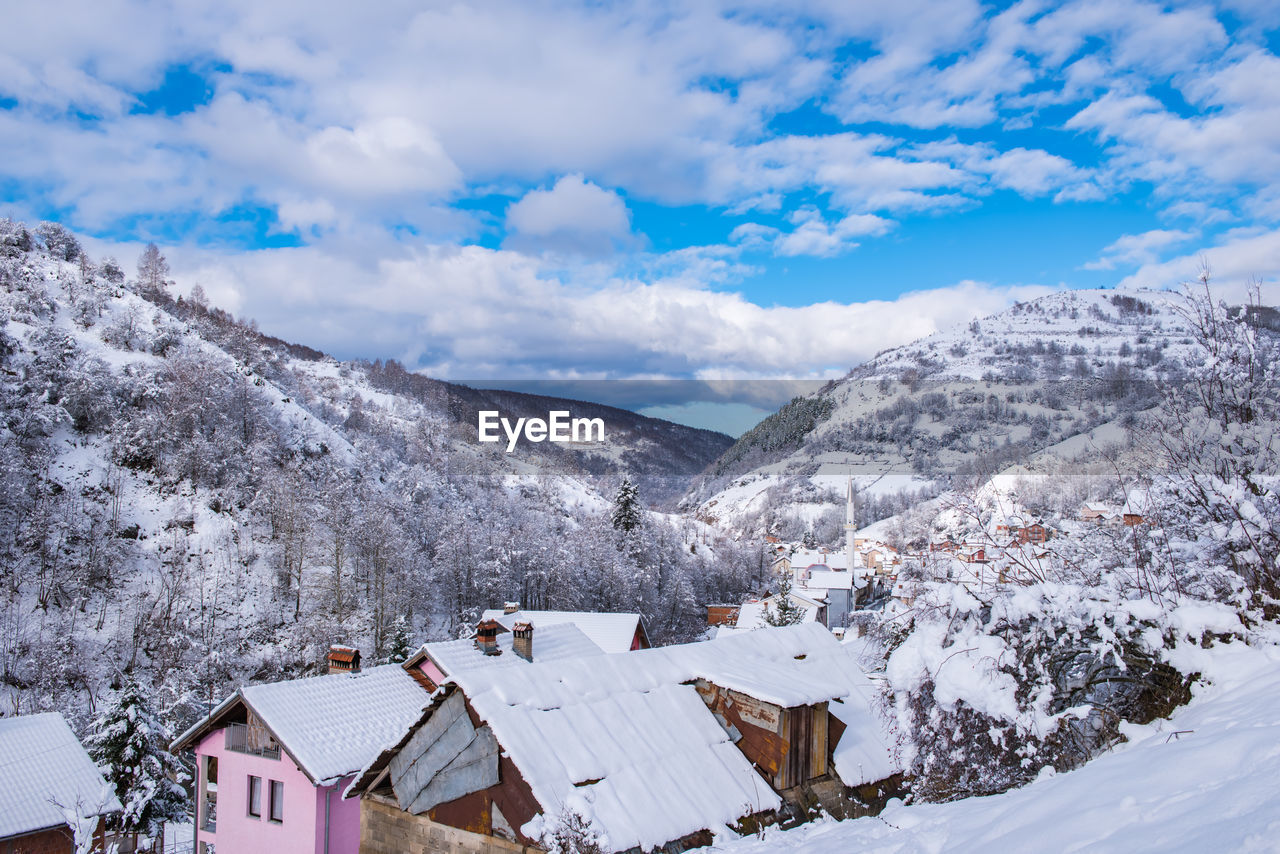 Houses on snowcapped mountain against sky