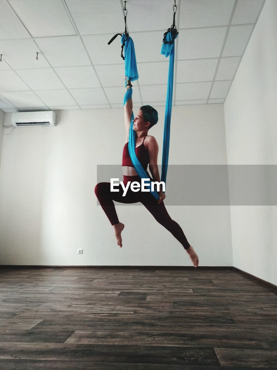 Low angle view of woman hanging on textile while exercising at home