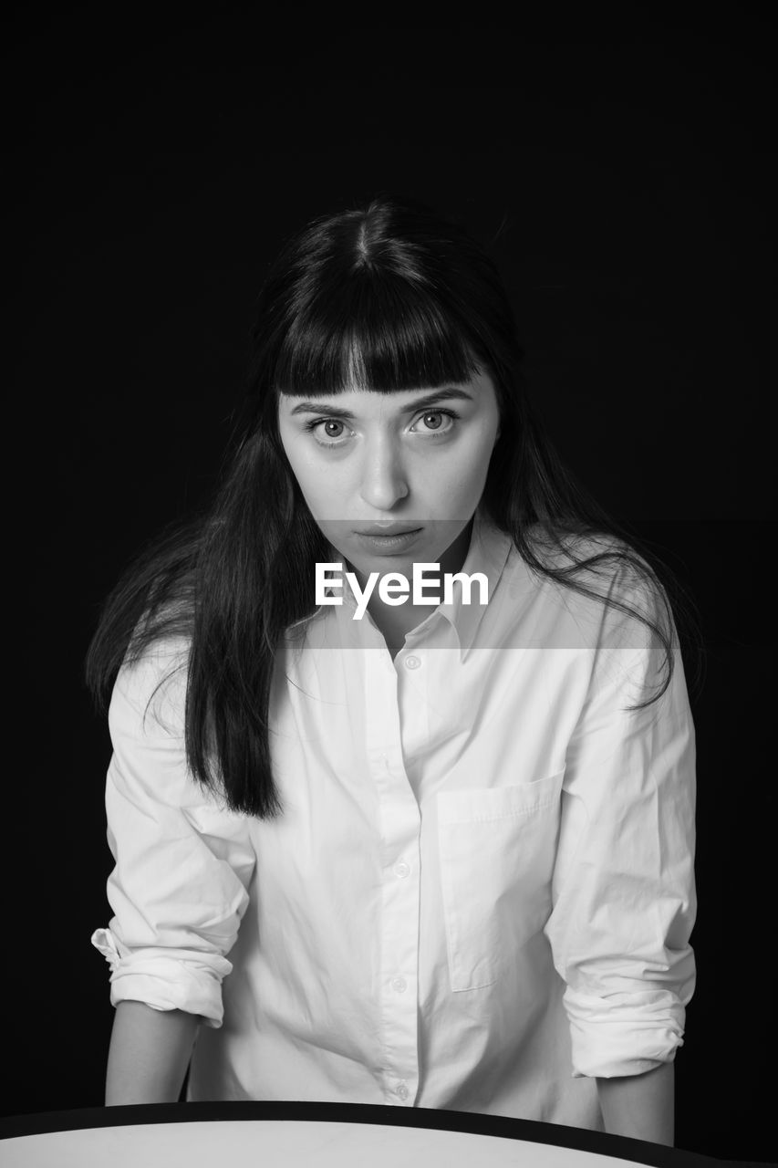 Portrait of young woman against black background