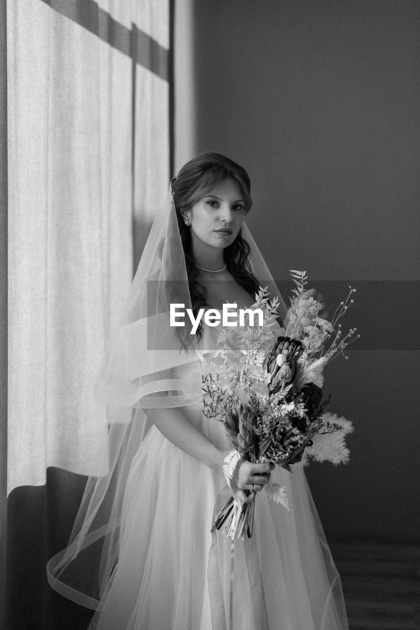 black and white, women, wedding dress, one person, bride, female, adult, flower, flower arrangement, celebration, bouquet, fashion, monochrome photography, young adult, indoors, event, newlywed, gown, wedding, clothing, bridal clothing, dress, flowering plant, monochrome, plant, portrait, emotion, veil, life events, standing, child, happiness, white, looking at camera, three quarter length, bridal veil, smiling, elegance, holding, looking, formal wear, lifestyles, person, nature, front view, love, hairstyle, childhood, positive emotion