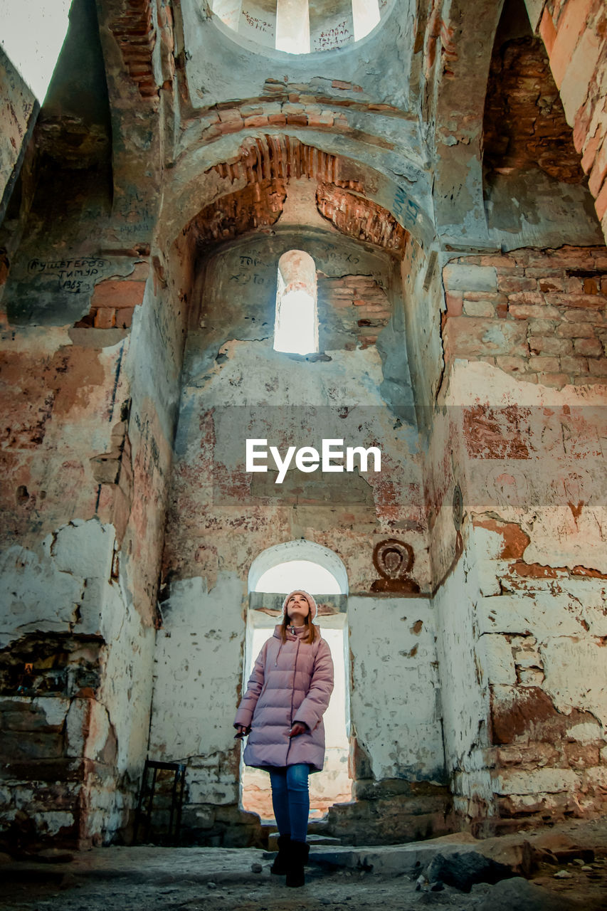 WOMAN STANDING AGAINST BUILDING