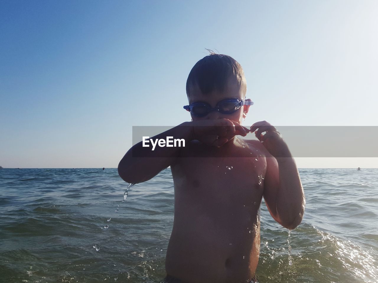 BOY IN SEA AGAINST CLEAR SKY