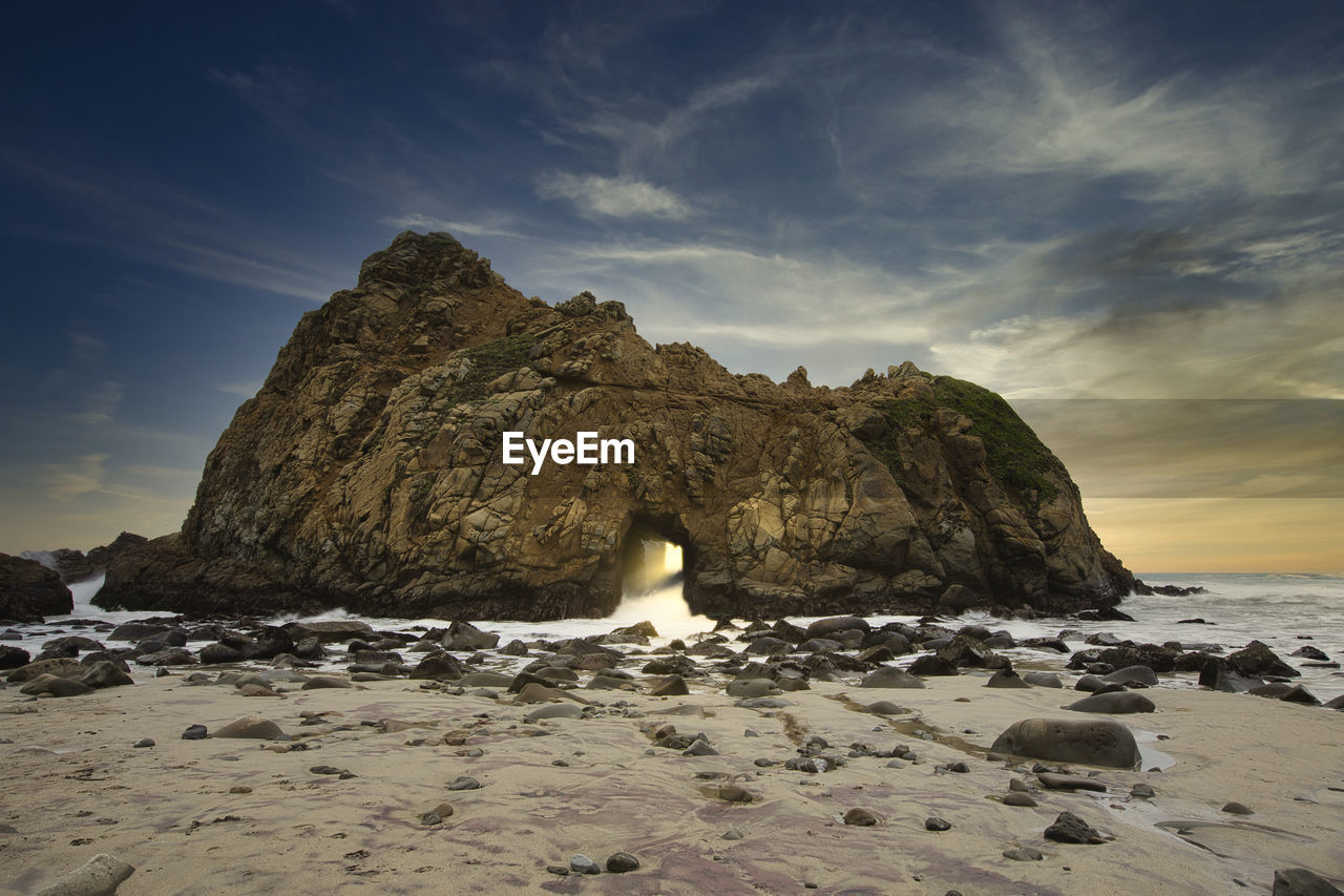 Rock formation on beach against sky