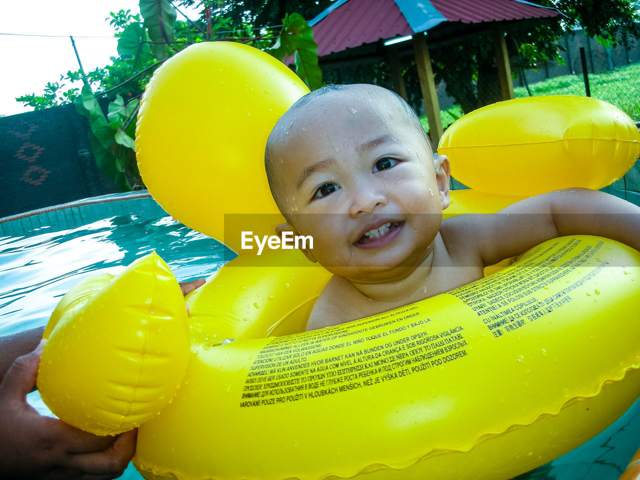 Cute boy with inflatable ring swimming in pool