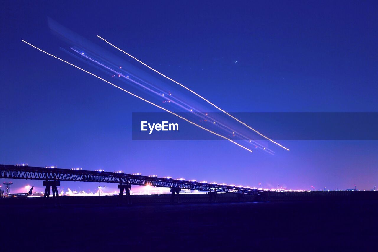 LOW ANGLE VIEW OF ILLUMINATED BRIDGE AGAINST BLUE SKY