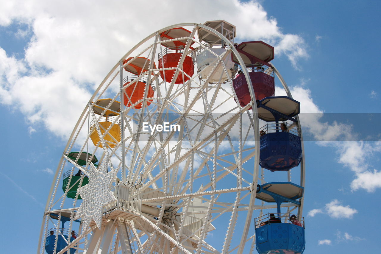 Low angle view of ferris wheel against cloudy sky