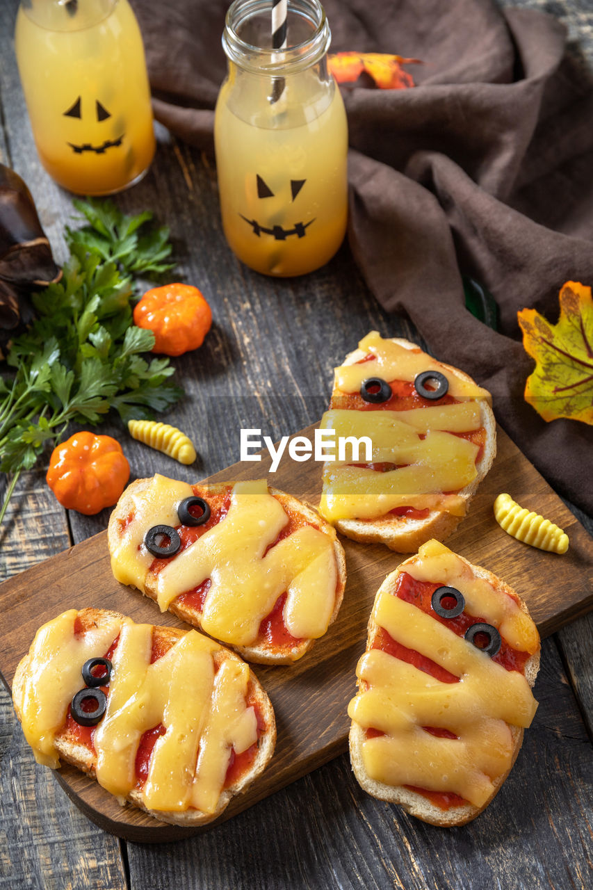 Halloween party food. halloween mummies mini pizzas on a wooden table.