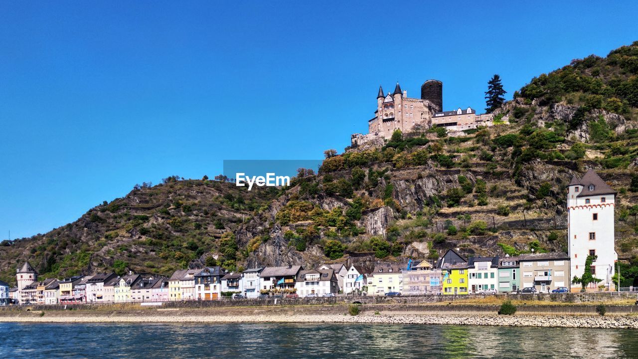 Buildings at waterfront against blue sky