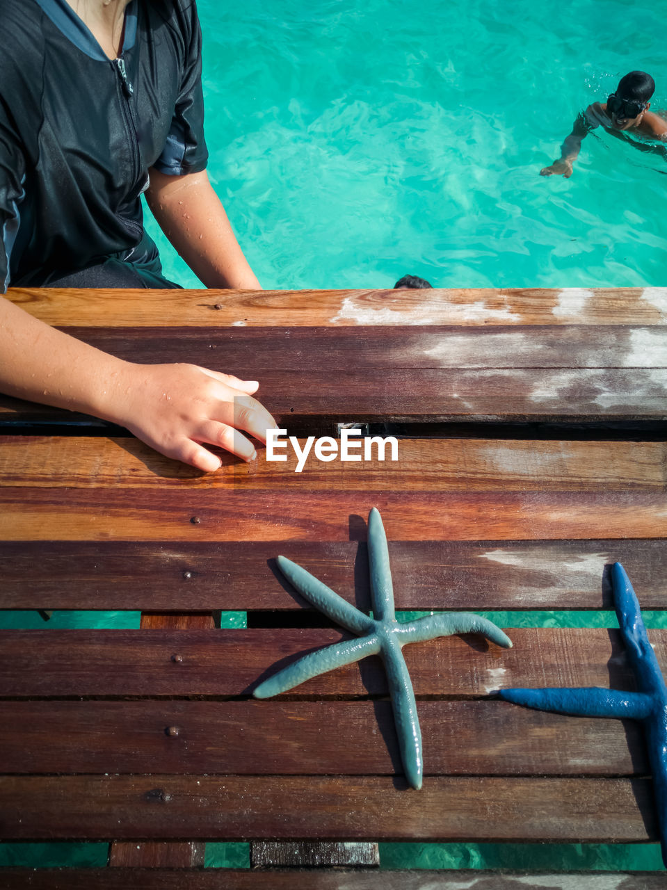 High angle midsection of man standing by wood in sea