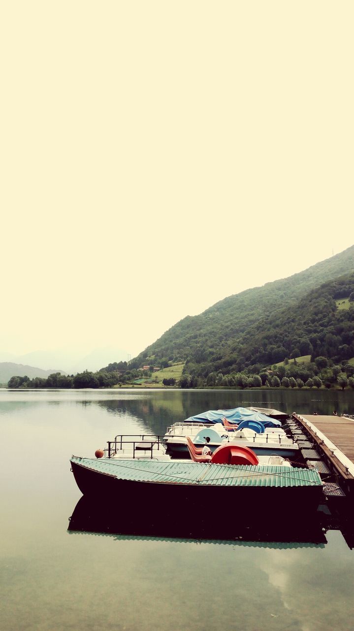 BOAT MOORED IN LAKE AGAINST SKY