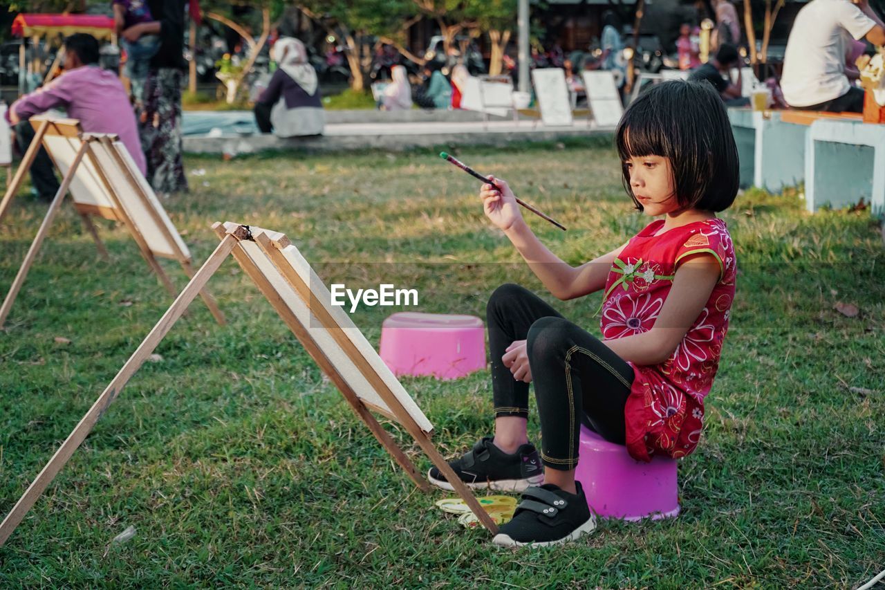 Side view of cute girl painting in park