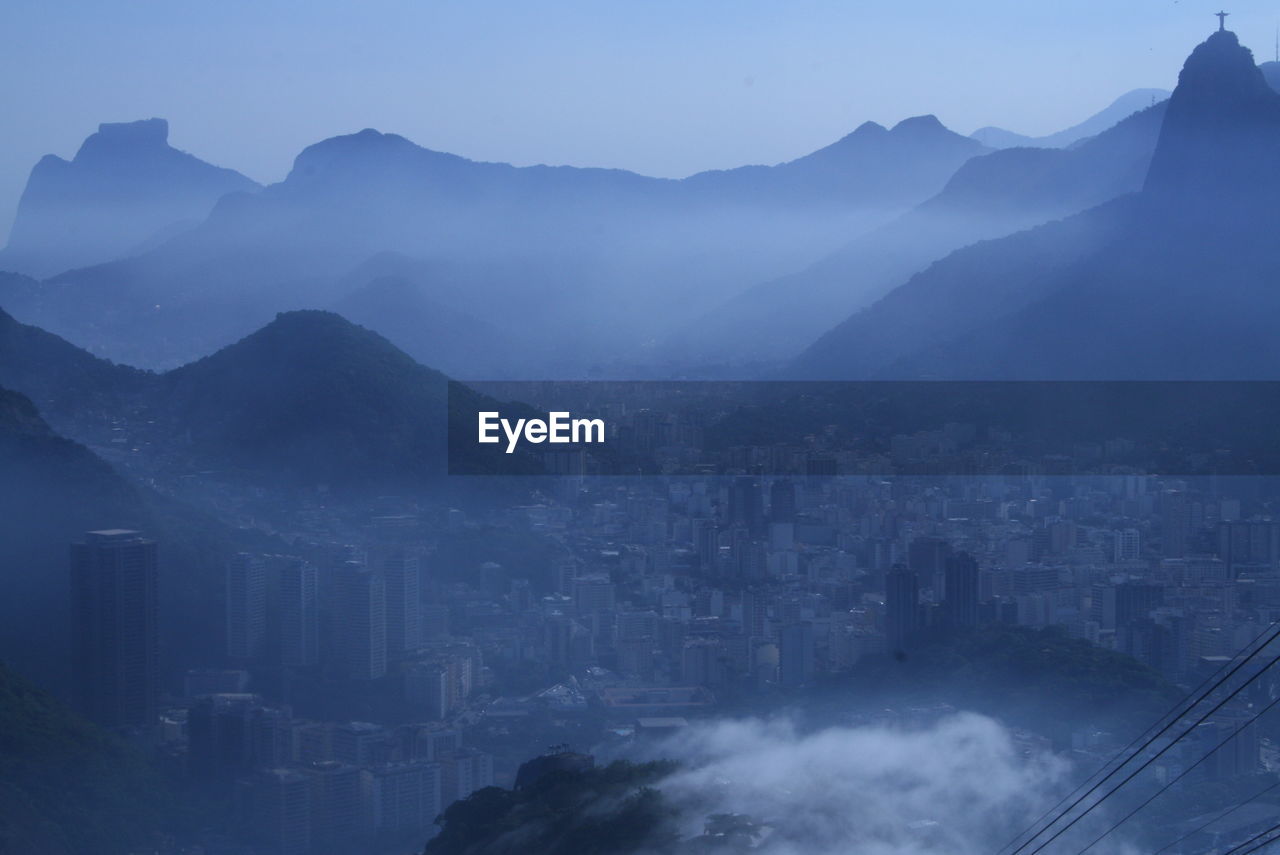 AERIAL VIEW OF CITYSCAPE AGAINST MOUNTAINS