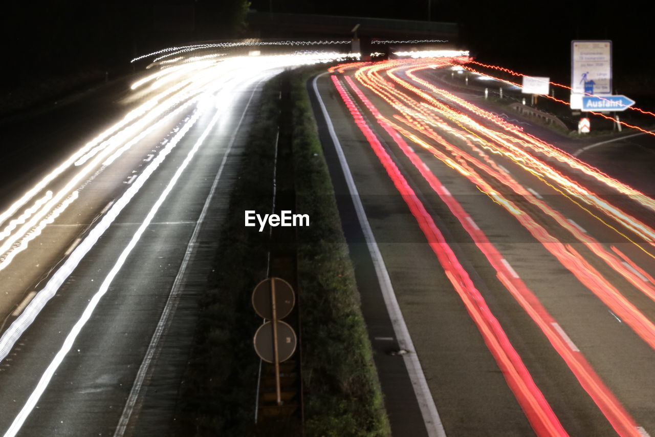 LIGHT TRAILS ON HIGHWAY AT NIGHT