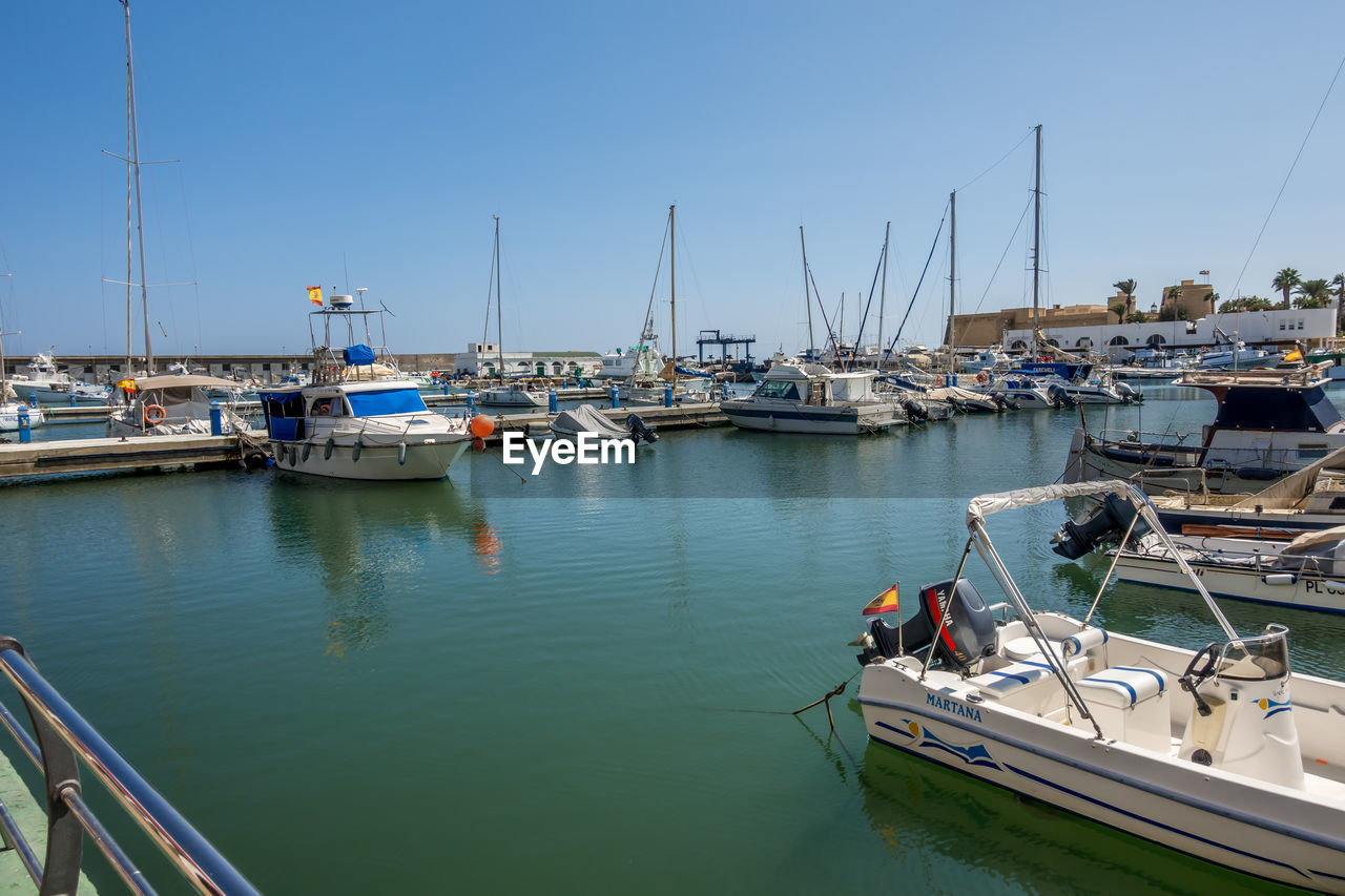 SAILBOATS MOORED AT HARBOR