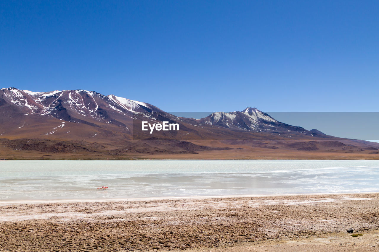 SCENIC VIEW OF SEA AND MOUNTAINS AGAINST BLUE SKY