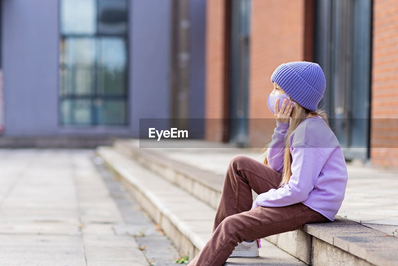 Side view of woman sitting on steps